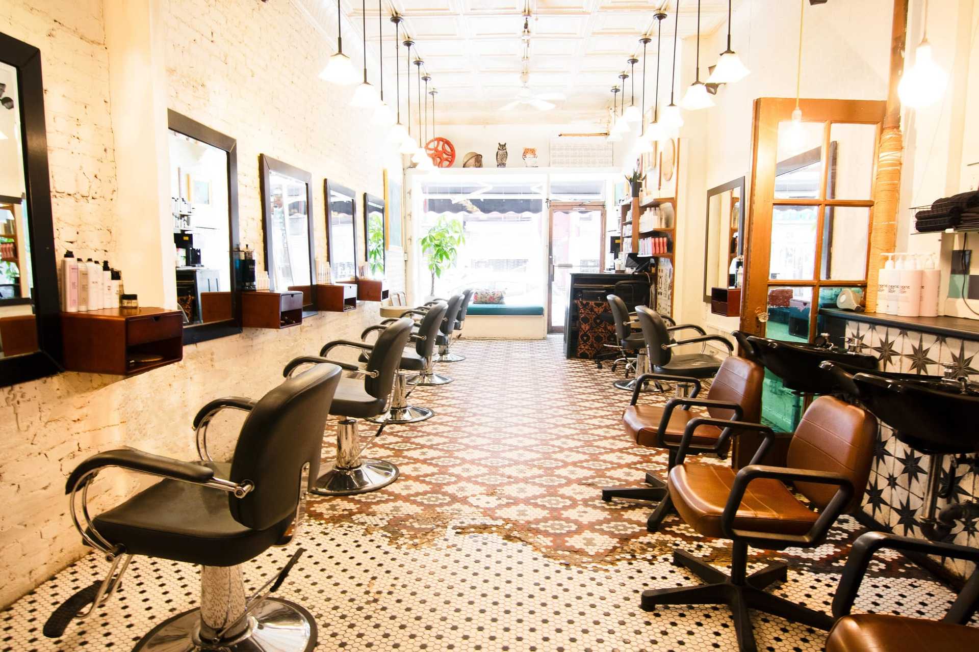 Chic, empty salon with vintage tiles, wooden mirrors, and styling chairs in a bright setting.